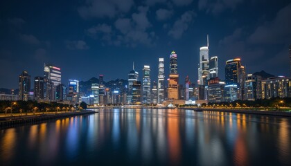 Fototapeta premium At night, the modern metropolitan skyline features illuminated skyscrapers, urban architecture, and long-exposed reflections of river water.
