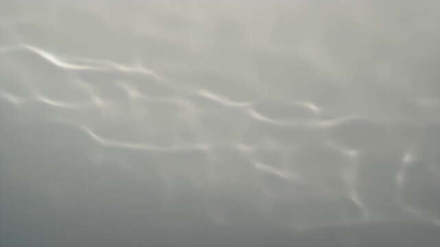 Soft light patterns undulate across a muted gray background