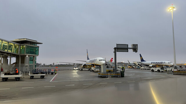Ryanair aircraft at Porto airport apron with ground service vehicles and jetways