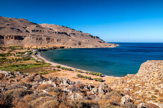 Rocky bay and small beach in Kato Zakros on southern coast of Crete Greece with clear blue Mediterranean sea and dry hills