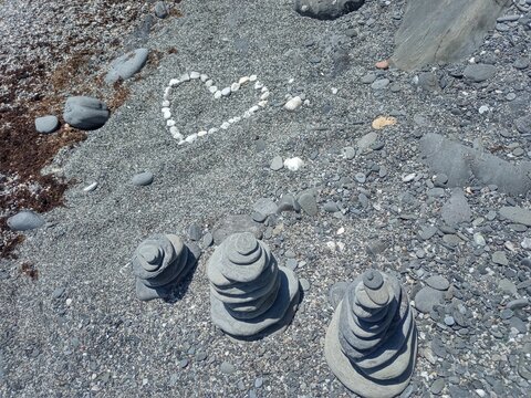 Tower of stones on beach dark sand and heart withe rocks