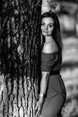 Fototapeta premium Female model with long dark hair wearing an off-the-shoulder top poses confidently in a monochrome portrait with a blurred background highlighting her features