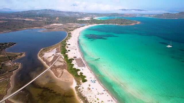 Sardinia San Teodoro Lu Impostu Beach Aerial 4K Video Drone Flight Along White Sand and Turquoise Sea with Dark Salt Lake View of Cala Brandinchi Bay Catamaran in Crystal Water Italy