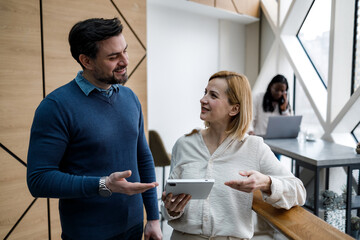 Fototapeta premium Couple talks with tablet in modern office space during afternoon hours