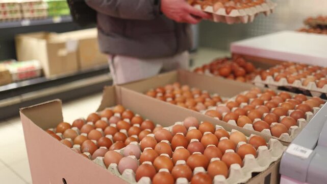The eggs in the egg tray are neatly arranged and sold in supermarkets in malls. Man buying fresh eggs in supermarket.