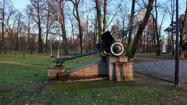 Soviet 76 mm divisional gun ZiS-3 on a concrete pedestal in a park, vintage artillery exhibit from World War II, military history monument among trees, field gun caliber 76 mm.