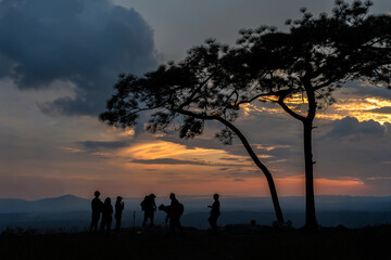 Fototapeta premium Silhouette traveler relaxing action on top mountain with sunset sky background.Group of happy tourists are having fun and treking on adventure nature trail.Active vacation concept.Happy and funny time