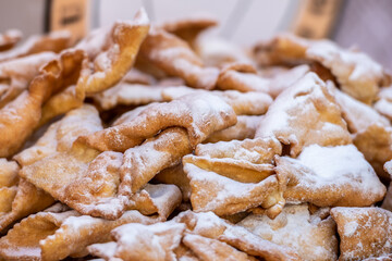 Fried pastries of Carnival, strips of fried dough typically made on Mardi Gras covered by powdered sugar, close up