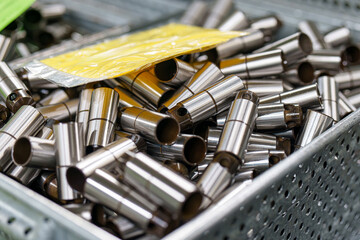 Metal tubes stacked together in a storage bin at a factory during daytime