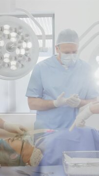 Vertical video: Surgeon rubbing gloves with patient on O2 mask, nurse reaching tray for surgery