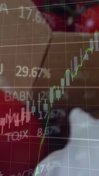 Vertical video: Gloved hand lifting tomato, showing finance chart rising, falling bars for markets