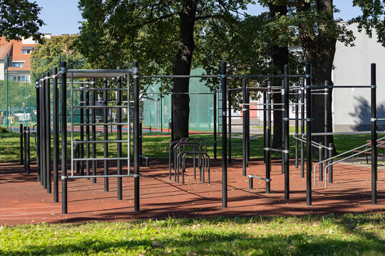 Modern outdoor calisthenics park with pull up bars and parallel bars on a rubber safety surface in a green city park. Street workout infrastructure for fitness and bodyweight training