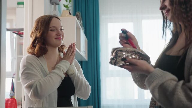 Casual Interaction Involving Woman Testing Lipstick By Window With Cheerful Expression, Spontaneous Moment Capturing Woman Examining Lipstick Color Next To Sunlight With Joyful Reaction