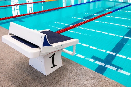A blue swimming pool with starting platforms, swimming lanes markings, red floating lane ropes and starting platforms.Number one platform for start and lane of swimming poolWater sports, indoor pool
