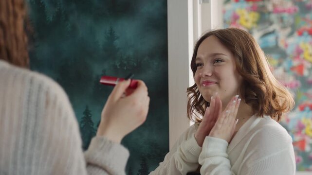 Joyful Makeup Moment, Expressive Scene Of Woman Laughing With Friend Holding Lipstick Nearby, Spontaneous And Cheerful Interaction Captured Between Woman And Friend During Makeup Unveiling