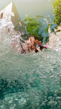 Young woman in blue swimsuit is swimming underwater in a pool, holding her breath and looking up at the surface while some air bubbles are coming out of her nose. Pretty girl with long hair is
