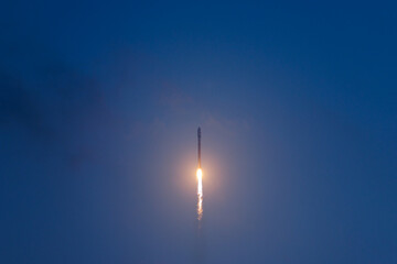 Fototapeta premium Rocket launching into dusk sky with glowing trail on background blue sky