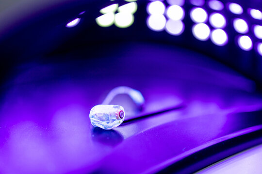Photograph of a hearing aid in an ultraviolet light device for disinfection. Concept of hearing aid hygiene.