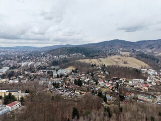 Obraz premium Valley town panorama. Elevated perspective of clustered homes on gentle slopes during overcast day
