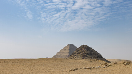Ancient step pyramid and stone cairn in Cairo, Egypt desert landscape under blue sky
