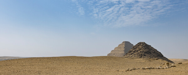 Ancient step pyramid and stone cairn in Cairo, Egypt desert landscape under blue sky
