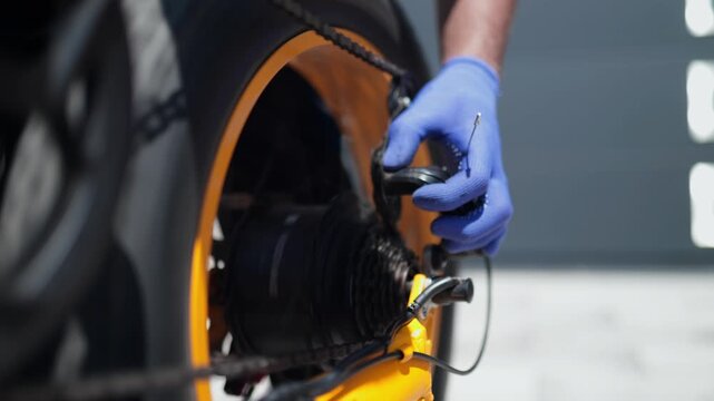 Close-up video of a bicycle mechanic wearing blue gloves adjusting the rear derailleur and drivetrain of a fat tire electric bike outdoors in bright daylight.