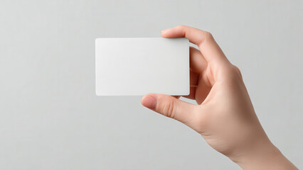 Obraz premium A person's hand holds a blank white card, ready for custom branding, text, or design against a neutral background.