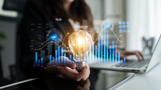 A business professional showcases a light bulb representing innovation alongside data analytics, graphs, and charts, highlighting growth and strategic thinking in a modern workspace. Scalp