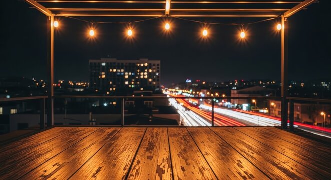 Wooden rooftop deck at night overlooking city skyline with traffic light trails and decorative string lights for product placement background