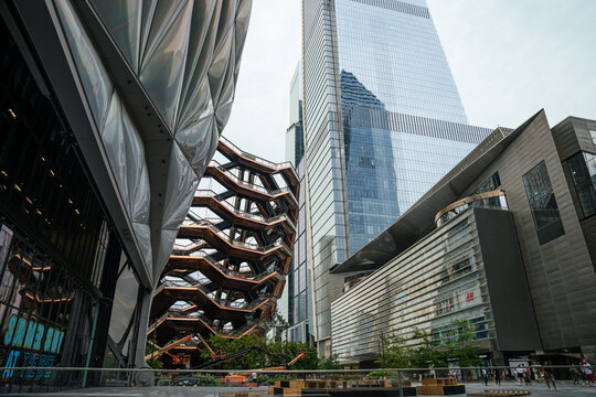 New York City, New York, USA - 08.02.2024: The Vessel sculpture stands in Hudson Yards surrounded by modern glass skyscrapers in Manhattan, New York City. The contemporary plaza highlights urban