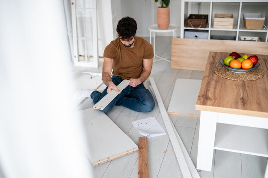 Young man assembling new flat pack furniture at home