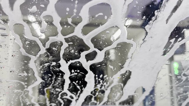 Static close-up of soap foam patterns on car wash windshield