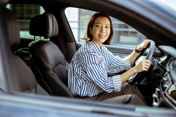 Korean woman driving a car in the city on a sunny day