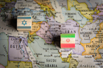 Naklejka premium Wooden blocks with Israel and Iran flags placed on a political map of the Middle East, symbolizing geopolitical conflict, regional tension, and international diplomatic crisis.