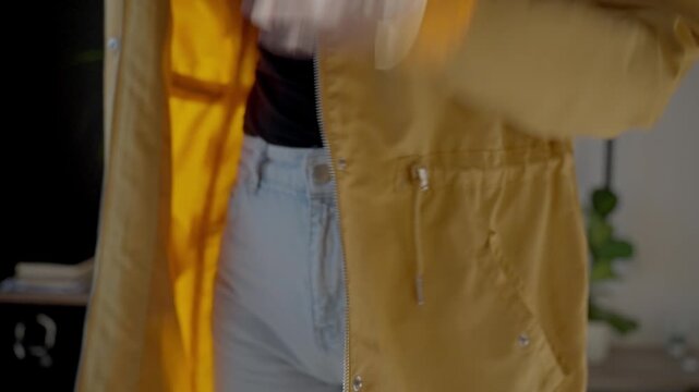 Closeup of woman hands unzipping yellow jacket. Concept of clothing change and casual outerwear
