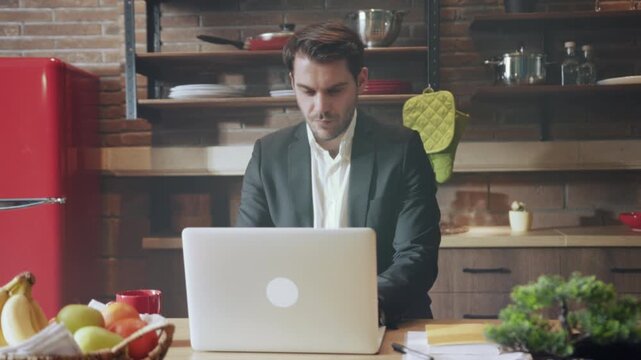 Casual professional workspace with kitchen elements, Individual focusing on laptop amidst kitchen and office items