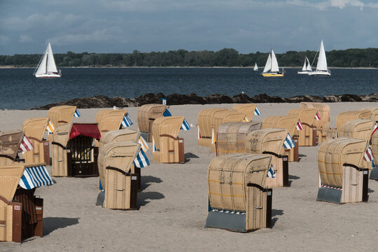 Sonniger Strand mit Strandk&ouml;rben und Segelbooten in Travem&uuml;nde
