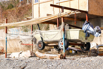 Fototapeta premium Stored boat under metal and wood canopy on gravel beach (55 chars)