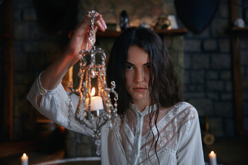 Mysterious woman with damp hair conducts occult ceremony amidst medieval stone walls
