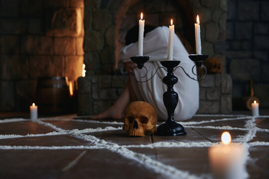 Woman kneeling behind candleholder near skull