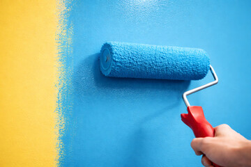 Obraz premium Painting wall with blue paint roller