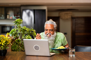 Obraz premium Modern Indian man multitasking with food and entertainment on laptop