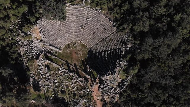 Drone slowly flying over  Telmessos Ancient City ruins nestled in a lush green mountain forest in Turkey, ab01