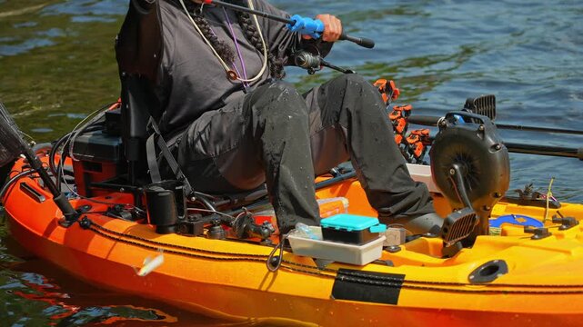 Woman setting up her tackles lure or bait to the braid line while slowly floating on water waves. Kayak sport fishing. Tourist enjoys kayak fishing at scenic coastline. Peaceful water setting at lake.