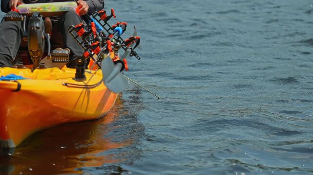 Woman setting up her tackles lure or bait to the braid line while slowly floating on water waves. Kayak sport fishing. Tourist enjoys kayak fishing at scenic coastline. Peaceful water setting at lake.