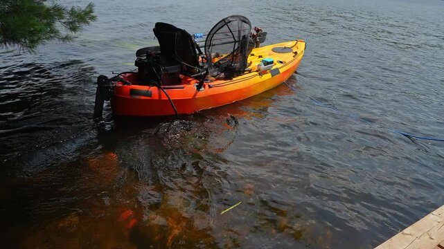 Testing electric trolling underwater motors of fully rigger kayak like drone watercraft mooring and tied to boat pier near cottage. Recreational watercraft, kayaking lake water craft equipment.