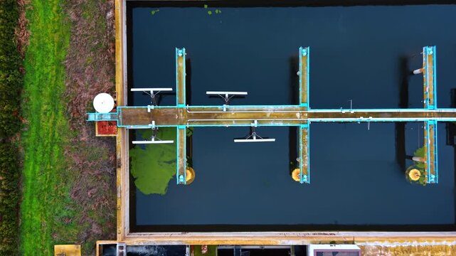 Flyover the pool filled with dark water. Approaching the tank with bubbling sewage. Waterworks facility.