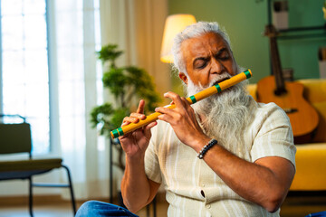 Practicing wooden flute at home, Indian mid age man doing riyaz at modern home © StockImageFactory