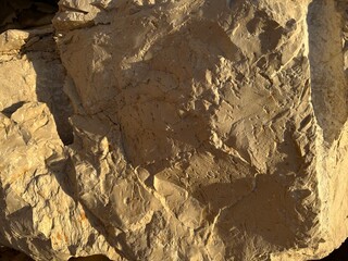 Obraz premium Rough fractured limestone rock surface in warm light