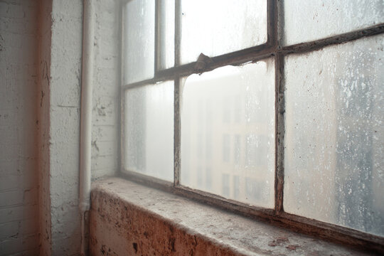 A foggy window of an old building with a blurred street view.